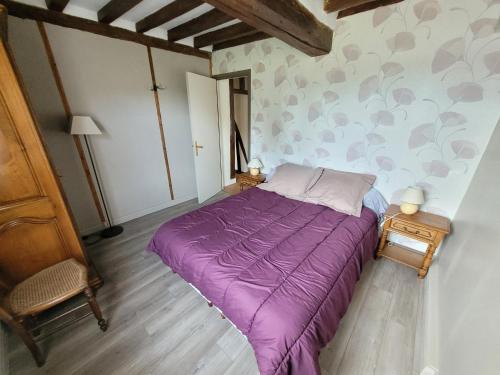 a bed in a room with a purple blanket at La Porterie face à l'abbaye in Le Bec-Hellouin