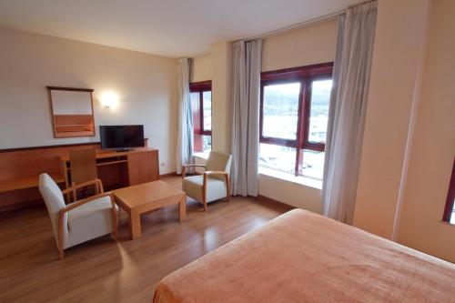 Habitación de hotel con cama, escritorio y sillas en Hotel Torques, en A Coruña