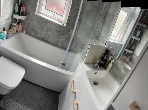 a bathroom with a white tub and a sink at Room in family home in Teversham