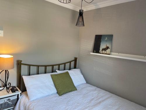 a bedroom with a bed with a green pillow on it at Room in family home in Teversham