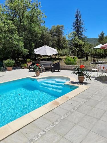 une piscine avec une table et un parasol dans l'établissement Villa le Bosquet en Luberon., à Ménerbes