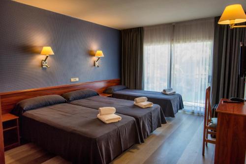 リョレート・デ・マルにあるHotel Acacias Suites & Spaのベッド2台と窓が備わるホテルルームです。