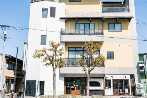 due alberi di fronte a un edificio di Guest House Ouka a Takayama