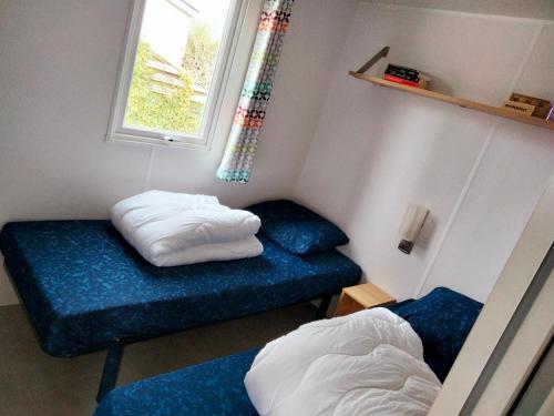 a room with two beds and a blue couch at BJ Chalets - Robbengat 85 - Gezellige, kindvriendelijke chalet op vakantiepark Lauwersoog! Vroege incheck! in Lauwersoog