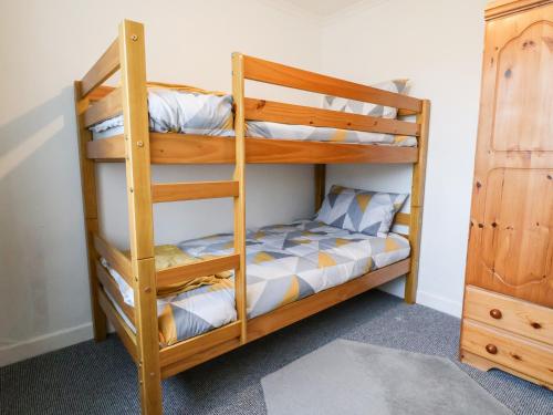 a bunk bed room with two bunk beds and a dresser at 17 Third Avenue in Prestatyn