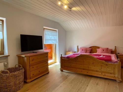 a bedroom with a bed with pink pillows and a flat screen tv at Idyllische Auszeit am Waldweg in Gmund am Tegernsee