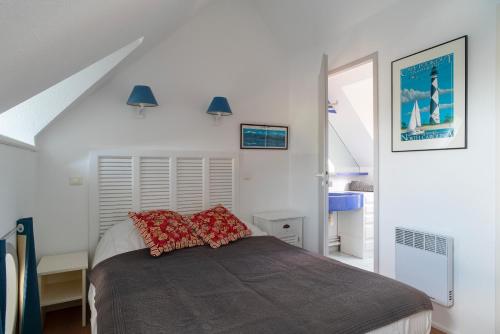 ein Schlafzimmer mit einem Bett mit roten Kissen darauf in der Unterkunft Plein Sud - Piscine partagée in Bénodet