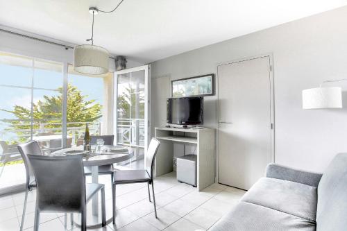 - un salon avec une table à manger et une télévision dans l'établissement Le Vent Marin - Magnifique vue mer, à Pléneuf-Val-André