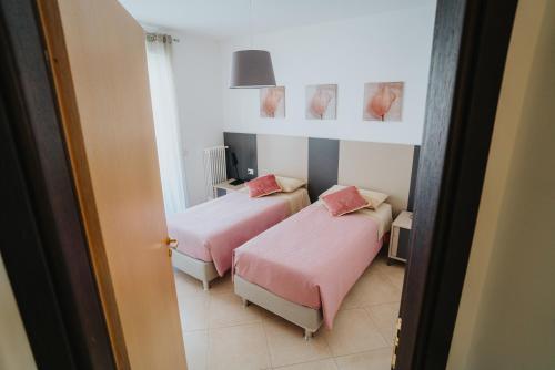 two beds in a room with pink sheets and pink pillows at Dimora Donna Matilde in Polignano a Mare