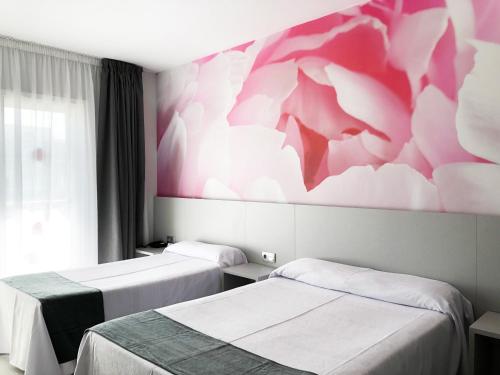 a room with two beds and a pink wall at Hotel Maria del Mar in Lloret de Mar