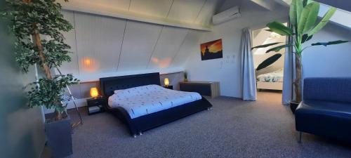 ein Schlafzimmer mit einem Bett, einem Sofa und einem Stuhl in der Unterkunft Vakantiewoning de Kei. Modern Achterhoeks genot in Lichtenvoorde