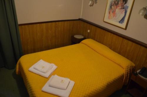 a bedroom with a yellow bed with two towels on it at Palace Hotel in Miramar