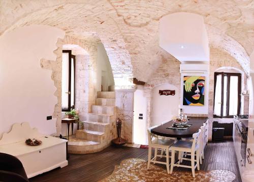 sala de estar con mesa, sillas y pared de piedra en L'Angolo di Gaudì, casa Milà, en Putignano
