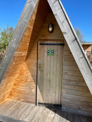 a wooden shed with a wooden door with a green cross at Achterhoeks Goed, Minicamping in Vragender in Vragender