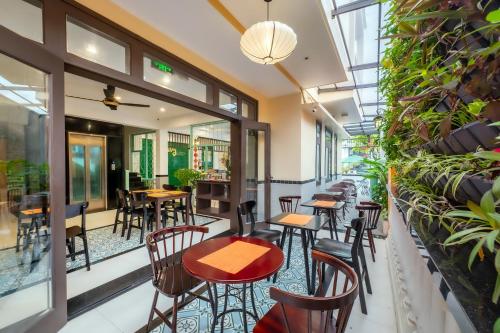 a restaurant with tables and chairs and windows at Hoi An Ivy Hotel in Hoi An