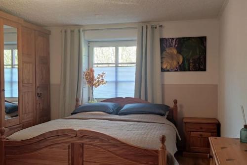 a bedroom with a bed with blue pillows and a window at Ferienwohnung Altneukoog in Tetenbüll