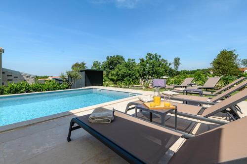 a pool with chairs and a table next to a swimming pool at Villa Oliva Muntrilj in Muntrilj