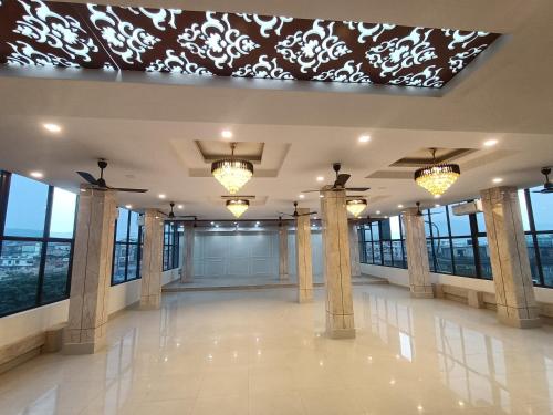 a large lobby with columns and lights and windows at Hotel Royal Palace in Guwahati