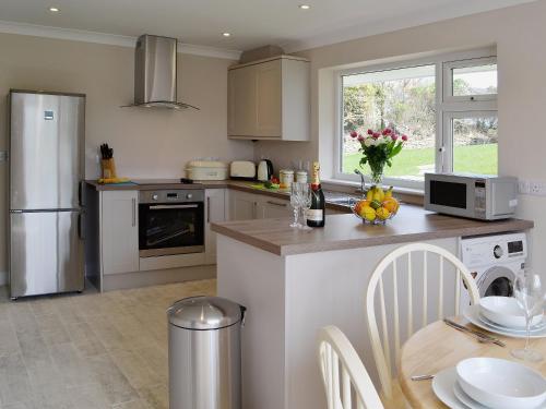 a kitchen with white appliances and a table with chairs at Silvershell View in Port Isaac