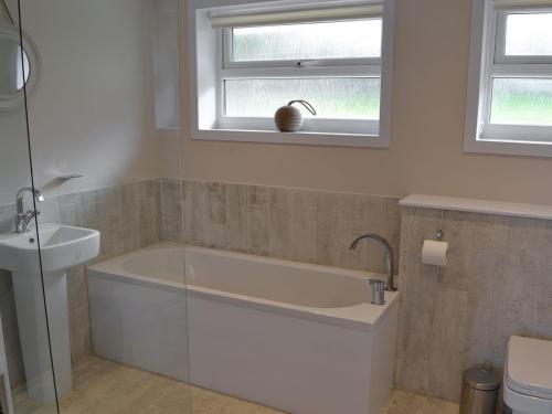 a bathroom with a bath tub and a sink at Silvershell View in Port Isaac