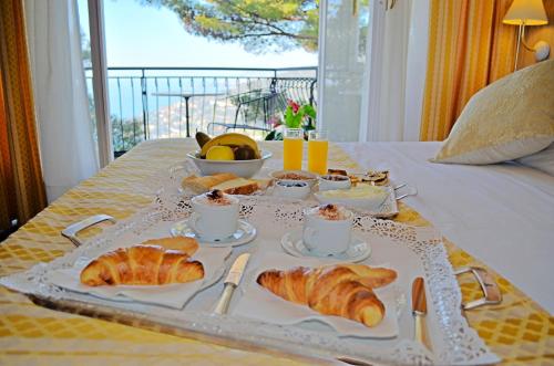 uma bandeja de pequeno-almoço com croissants e café numa mesa em La Riserva di Castel d'Appio- Charme & Relax em Ventimiglia
