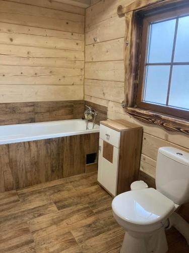 a wooden bathroom with a toilet and a bath tub at Chata Peťo in Bžany