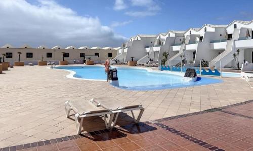 a large swimming pool in a resort with chairs and buildings at ON THE BEACH in Costa Teguise