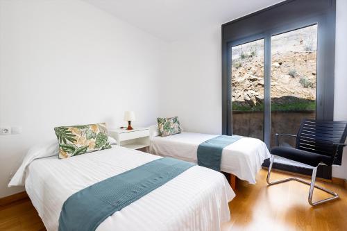 een kamer met 2 bedden, een stoel en een raam bij RNET - Casa 3 - Vista Mar Almadrava Roses in Roses