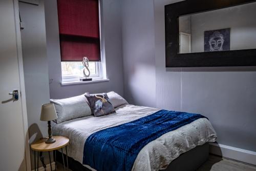 a bedroom with a bed with a blue blanket and a mirror at Spacious Liverpool Central Apartment in Liverpool