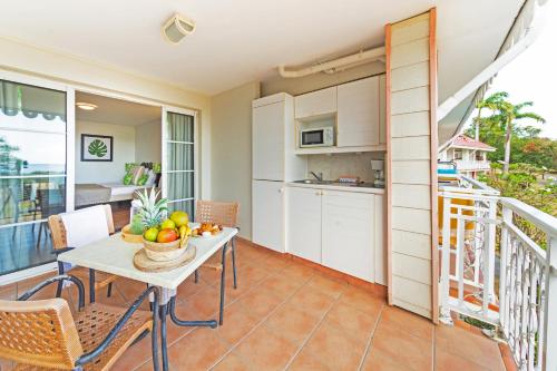 a kitchen and dining room with a table with a bowl of fruit at Village Pierre & Vacances Sainte Anne in Sainte-Anne