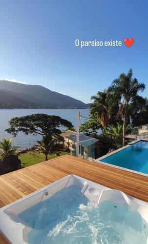 a hot tub on a deck with a view of the water at Paraíso da Enseada de Brito in Palhoça