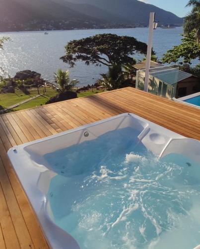 a hot tub on a deck with a view of the water at Paraíso da Enseada de Brito in Palhoça