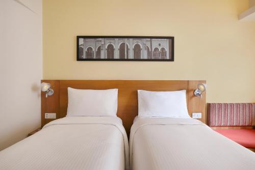 two beds in a room with a picture on the wall at ibis Coimbatore City Centre - An Accor Brand in Coimbatore