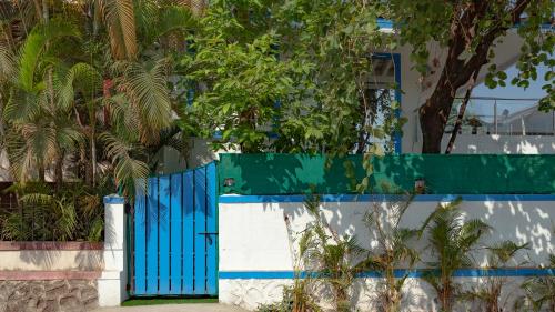 a blue gate in front of a wall with trees at Cozy Nook- Artsy 3BHK with Private Pool- Lonavala By StayMonkey in Lonavala