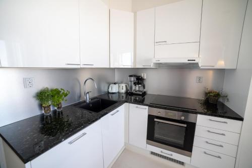 a kitchen with white cabinets and a black counter top at Meritähti Apartments by Hiekka Booking in Kalajoki