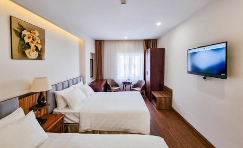 um quarto de hotel com duas camas e uma televisão de ecrã plano em Xavia Hotel Quy Nhơn em Quy Nhon