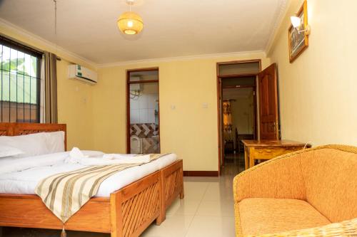 1 dormitorio con 1 cama, 1 sofá y 1 silla en Runako Lodge, en Arusha