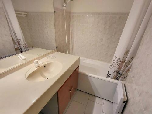een witte badkamer met een wastafel en een bad bij Appartement Six-Fours-les-Plages, 2 pièces, 4 personnes - FR-1-316-295 in Six-Fours-les-Plages