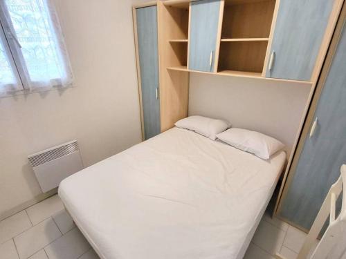 een kleine slaapkamer met een wit bed en planken bij Appartement Six-Fours-les-Plages, 2 pièces, 4 personnes - FR-1-316-295 in Six-Fours-les-Plages