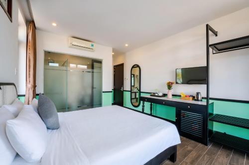 a bedroom with a white bed and a desk at Hoi An Ivy Hotel in Hoi An