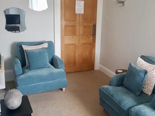 a living room with two blue chairs and a door at Pebbles in Lynton
