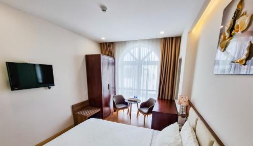a hotel room with a bed and a tv and a table at Xavia Hotel Quy Nhơn in Quy Nhon
