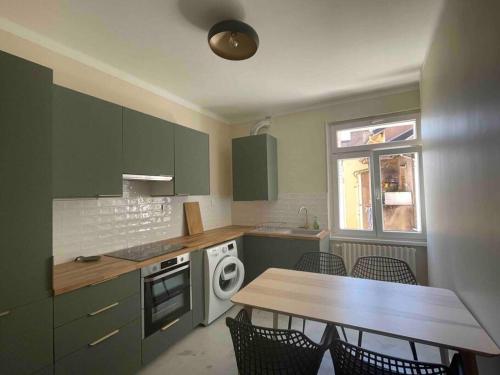 uma cozinha com armários verdes e uma mesa com cadeiras em Les chambres du Graoully - Le 109 - Metz Gare - Parking inclus - NO S-model em Metz