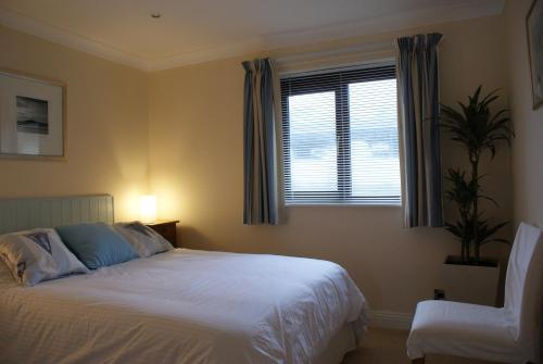 1 dormitorio con cama, ventana y silla en 23 Burgh Island Causeway, en Bigbury-on-Sea