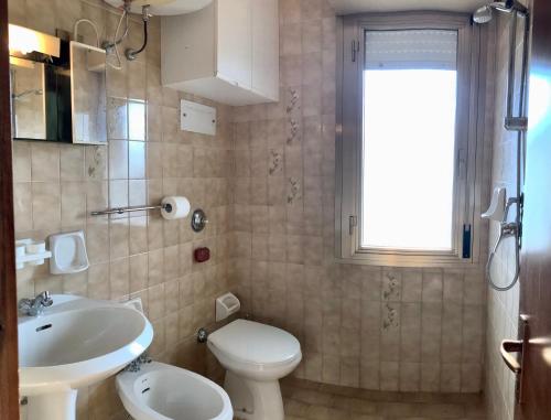 a bathroom with a white toilet and a sink at Condominio Aquila in Bibione