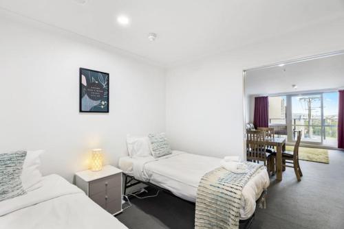a bedroom with two beds and a table with a chair at Superb 2BR Aprt in Central City - Wifi - Netflix in Auckland