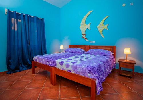 a bedroom with a bed with purple sheets and blue walls at Villa Lagosta Stella Maris Exclusive in Vila do Porto