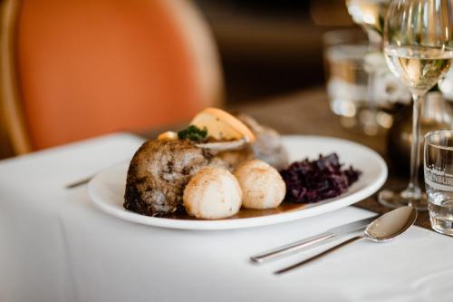 a plate of food on a table with a glass of wine at Hotelpark Bodetal mit Ferienwohnungen in Thale