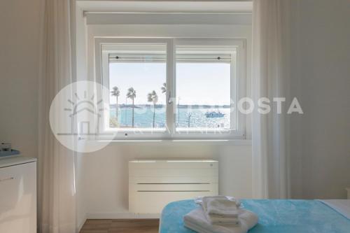 a white bedroom with a window with palm trees at L'Ormeggio in Porto Cesareo