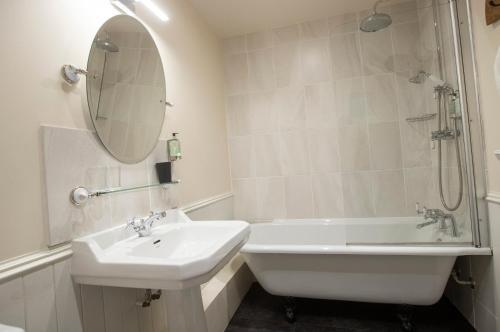 a bathroom with a sink and a tub and a mirror at Cardhu Country House in Aberlour